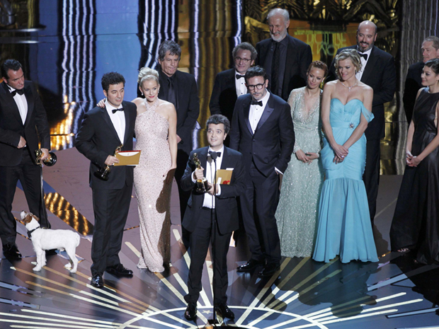 Com elenco e equipe de 'O artista' ao fundo, produtor Thomas Langmann discursa no Oscar após longa vencer o prêmio de melhor filme (Foto: Gary Hershorn/Reuters)